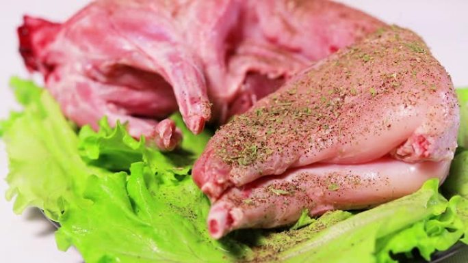 厨师在兔肉上撒上欧芹。肉类腌料，烹饪中的肉类
