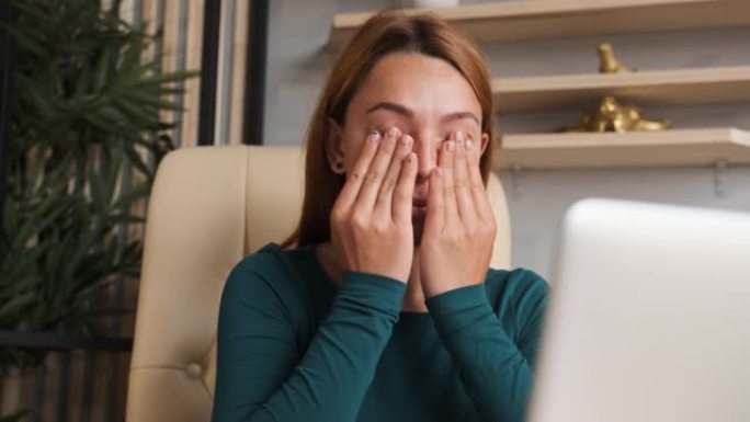 女人厌倦了坐在电脑前工作。她用乏力擦眼睛。
