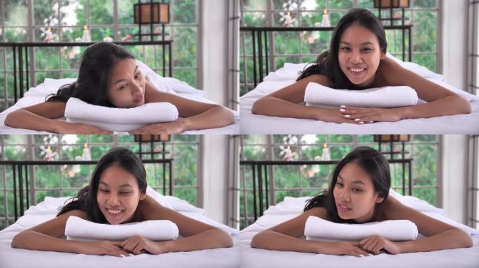快乐的年轻亚洲女性躺在水疗沙龙的按摩床上。