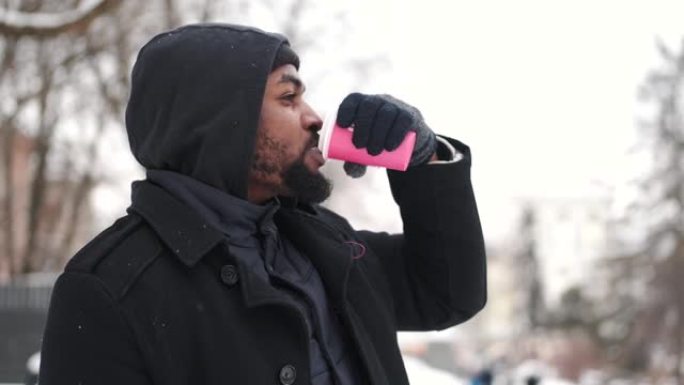 穿着连帽衫的年轻非洲裔美国人在冬天喝咖啡去户外