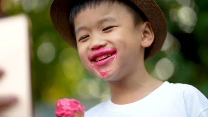 亚洲男孩舔融化的冰淇淋和微笑。幸福与夏天的概念