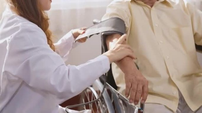 护士测量血压检查沉思的残疾老年患者坐在轮椅上