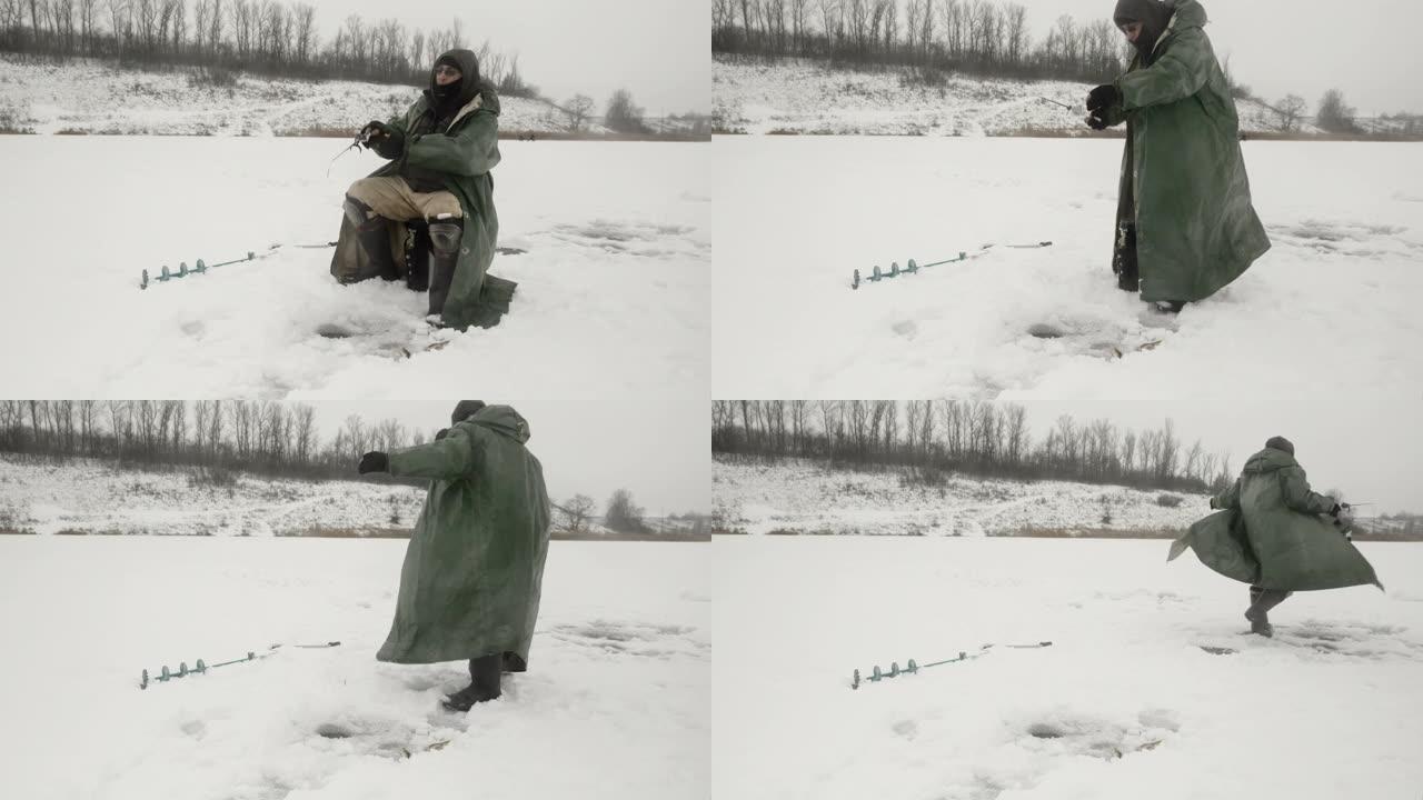 冬季钓鱼概念。穿着冬季极端衣服的渔夫正在冰洞里抓鱼。人在冰冻的湖上钓鱼