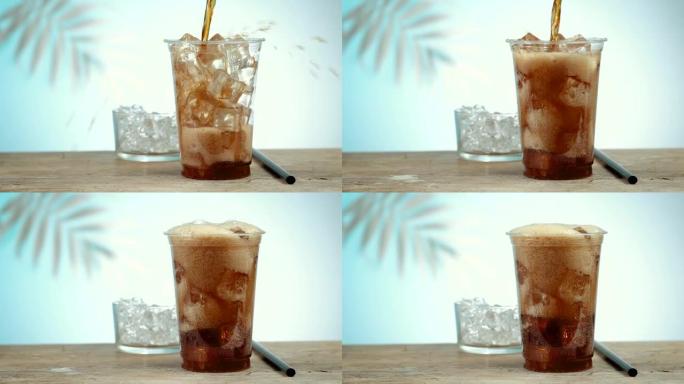 新鲜的可乐饮料在塑料外卖杯中与冰块形成泡沫和飞溅，背景中散焦的棕榈叶。慢动作