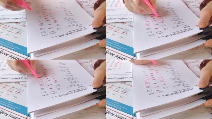 用粉红色的记号笔在一张有财务信息的纸上做笔记