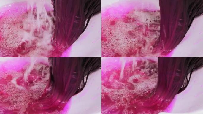 发型师在水槽上着色后洗客户粉红色的头发