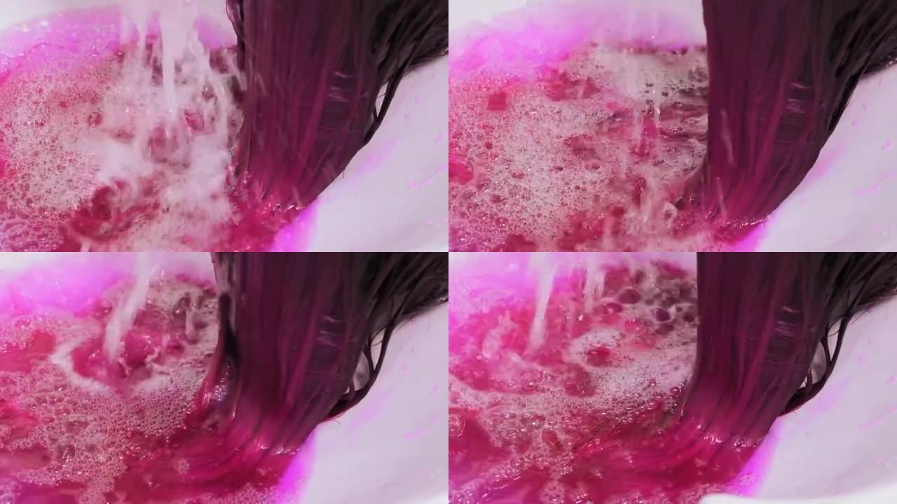 发型师在水槽上着色后洗客户粉红色的头发