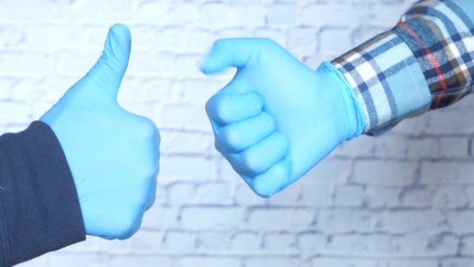 两人手持医用手套的特写镜头显示拇指向上。