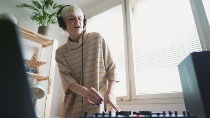 年轻的女DJ在家庭音乐工作室播放现场音乐时跳舞