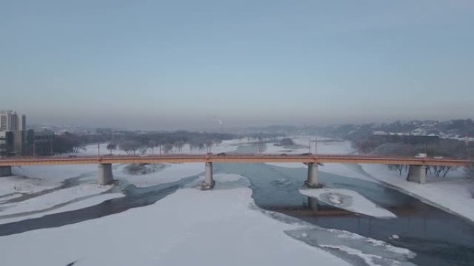 在立陶宛考纳斯前方冰冷的河流和桥梁上飞行的空中4k镜头