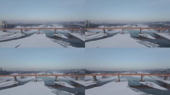 在立陶宛考纳斯前方冰冷的河流和桥梁上飞行的空中4k镜头