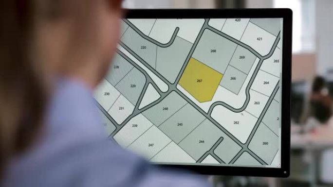 妇女在办公室的计算机上使用数字地籍地图土地登记数据库。待售建筑地块