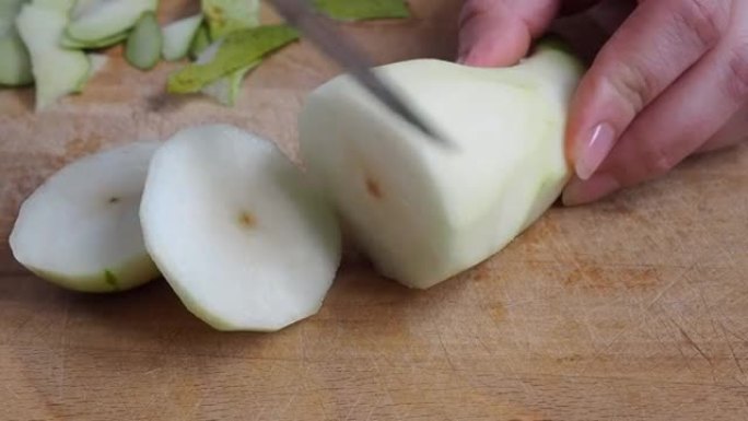 成熟的梨子会议用刀在木砧板上切成薄片。