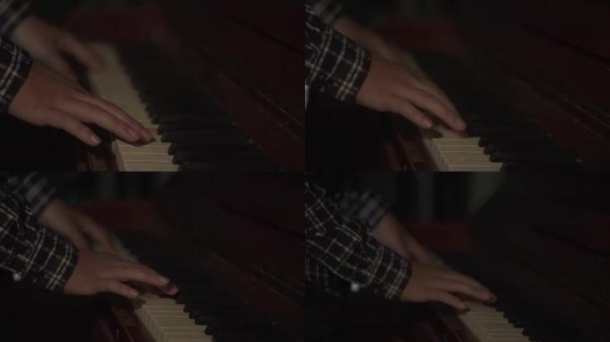 男性手在钢琴特写上演奏得很大。晚上，一位音乐家键盘手在黑暗中弹奏旧钢琴。