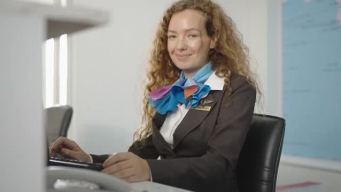 在值机柜台工作的高加索女航空公司员工的肖像，微笑着看着相机