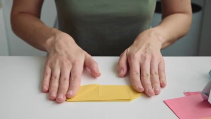 折纸课。女人用彩纸做折纸复活节兔子。DIY概念