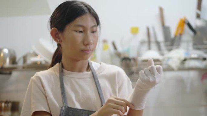 亚洲女孩戴着手手套将爆米花装在塑料袋中，准备食用。