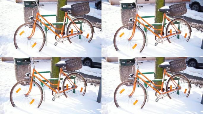 一辆橙色自行车站在雪地里。温暖地方天气急剧变化。