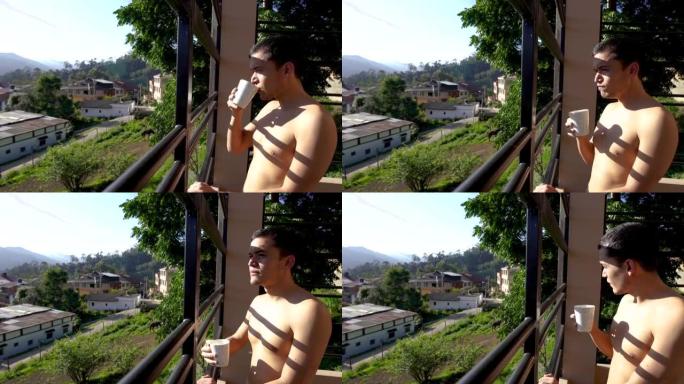 拉丁男人在房间的阳台上没有衬衫，喝杯咖啡，欣赏风景