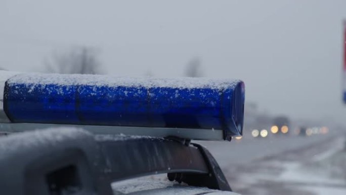 傍晚，警车的蓝色灯光在雪地上闪烁。特写镜头