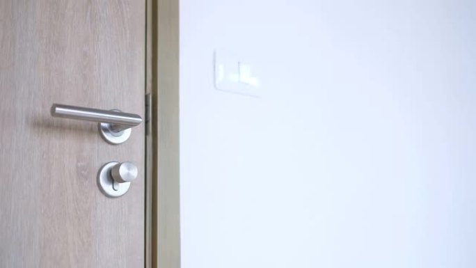 一个穿着灰色毛衣的女人在房间里转动门锁旋钮以确保公寓的安全。