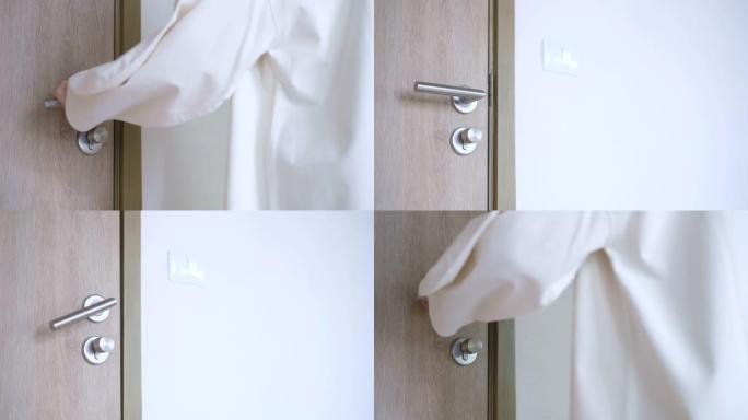一个穿着灰色毛衣的女人在房间里转动门锁旋钮以确保公寓的安全。