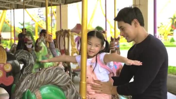 亚洲爸爸和他的女儿玩旋转木马。