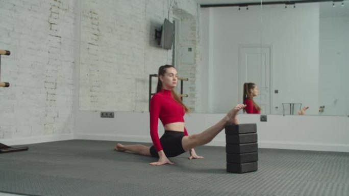 运动健康的女人用瑜伽块劈开