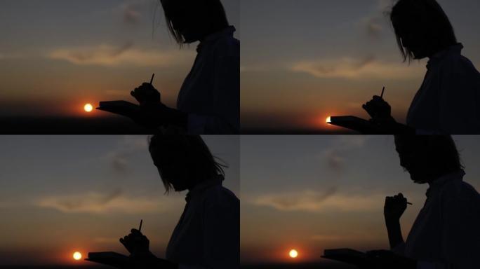 在日落时画画的艺术家的剪影