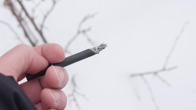 闷烧香烟的特写镜头。手握着一支吸烟的香烟。