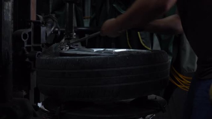 机械师应用润滑脂，通过轮胎去除机械设备修复去除汽车轮胎胎面的旧损坏和磨损。工程师在汽车维修车库的车间
