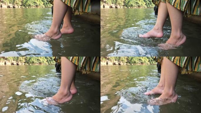 一个穿着休闲服装的长发亚洲女人坐在河里的清水里泡脚