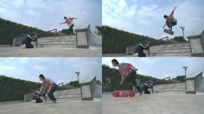 一名亚洲男子在滑板公园白天拍摄他的朋友在楼梯上滑板的照片的慢动作镜头