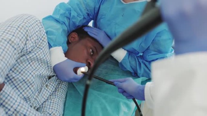 当代手术室手术中的非洲裔美国人。医生通过一个年轻的非裔美国人的嘴进行内窥镜检查，插入管状胃镜。仪器内