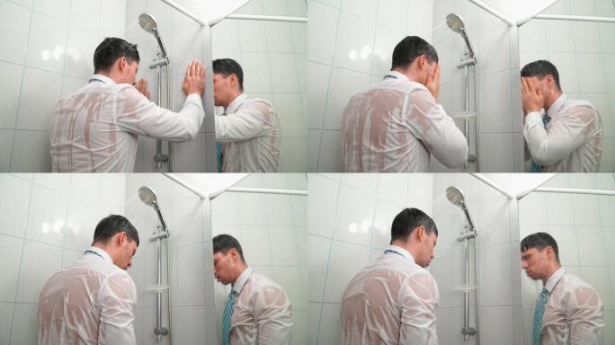 穿衬衫打领带的伤心男人站在浴室的淋浴下，穿着衣服洗澡