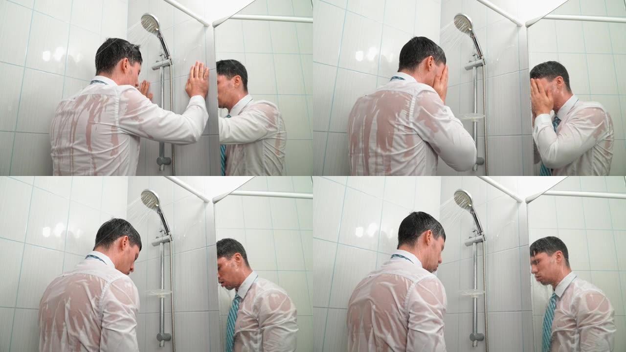 穿衬衫打领带的伤心男人站在浴室的淋浴下，穿着衣服洗澡
