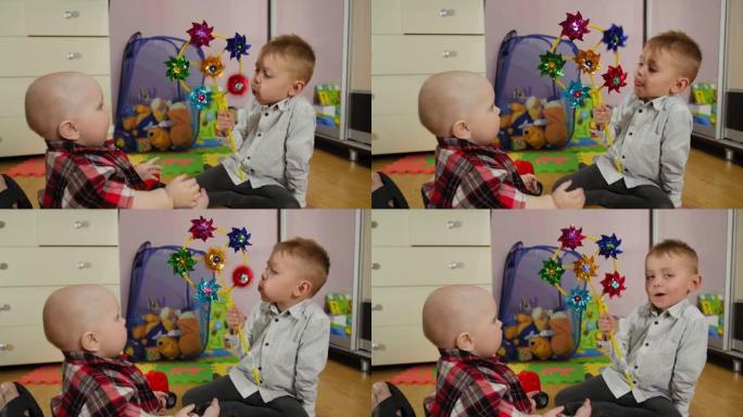 小男孩在家为有趣的九个月大的弟弟吹玩具风车螺旋桨。