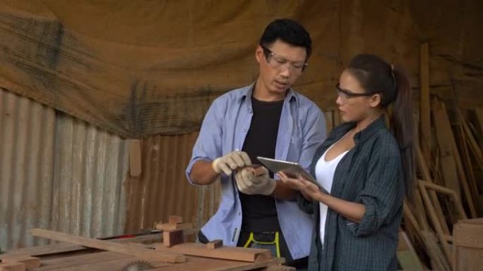 亚洲男女都是手握平板电脑的熟练木匠，在网上卖木家具，在网站上卖东西
