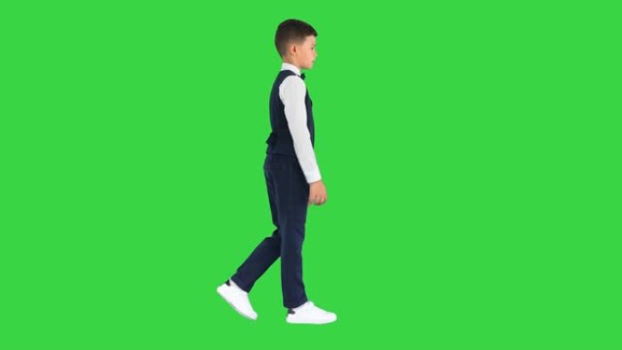 穿着领结和背心的小男孩在绿色屏幕上挥舞着双手，色键