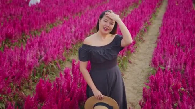 年轻迷人的亚洲女性穿着休闲装沿着红色美丽的花朵行走带着积极的情感自然农场漫游独自旅行概念
