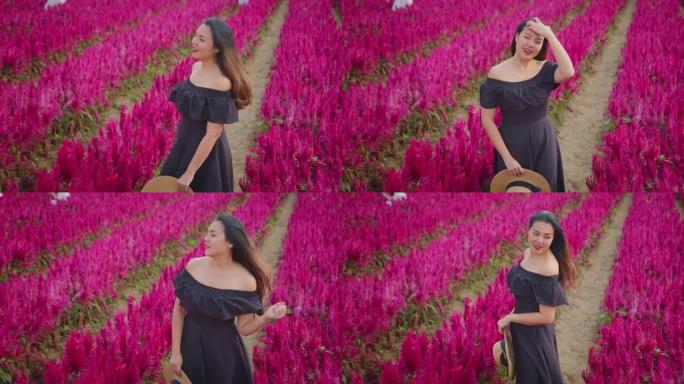 年轻迷人的亚洲女性穿着休闲装沿着红色美丽的花朵行走带着积极的情感自然农场漫游独自旅行概念