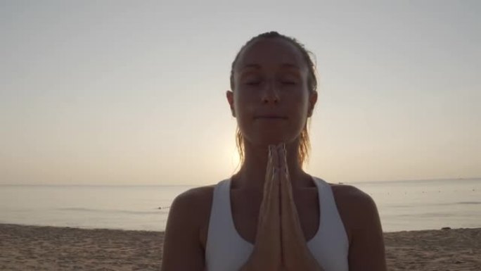 封闭起来，年轻女子在日落时冥想祈祷。日落时在海滩上练习瑜伽的女性姿势