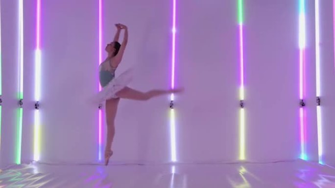 一位年轻女子在多色霓虹灯的背景下，在工作室里跳舞古典芭蕾舞的元素。穿着芭蕾舞短裙和脚尖鞋的芭蕾舞女演