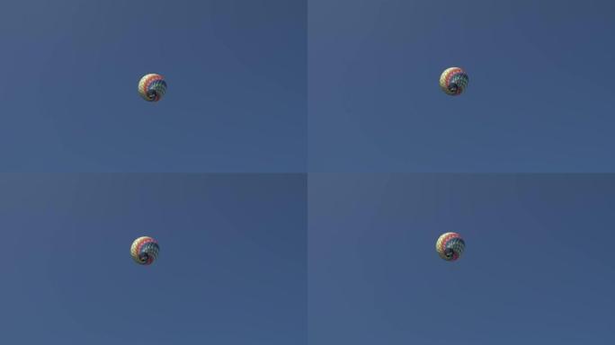一个带有篮子的彩色热气球在蓝天上飞翔。从地面看。