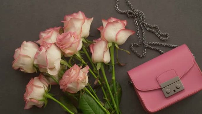 一束粉红玫瑰和桌子上的手拿包。为聚会做准备。