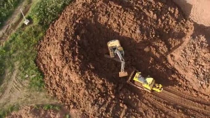 推土机的鸟瞰图正在刮擦一层土壤，挖掘机正在挖掘和倾倒污垢