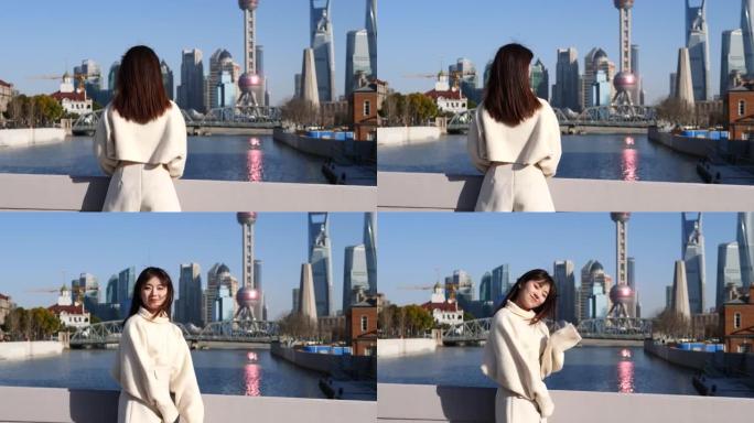 美丽的中国年轻女子回头挥手向上海外滩地标背景打招呼，4k慢动作镜头。