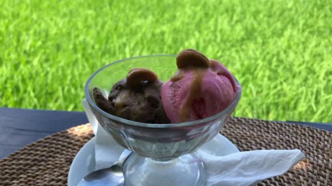 绿草背景上柳条木制底座上的花瓶中的巧克力和水果冰淇淋