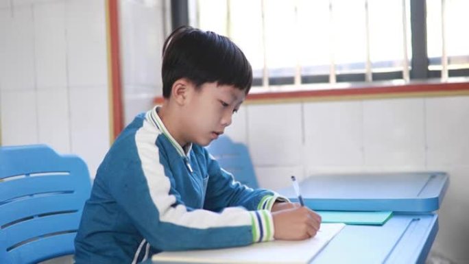 亚洲小学生在课堂上做作业时思考