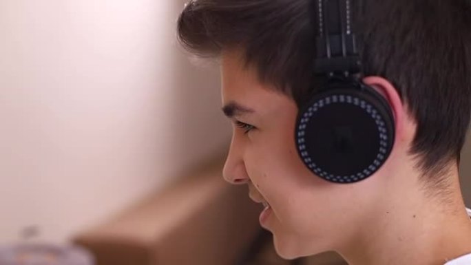 戴着无线耳机的年轻十几岁男孩在玩游戏时与朋友交谈的特写镜头